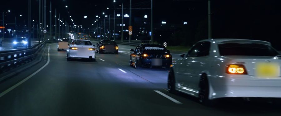 Japanese cars in a convoy on a city road at night
