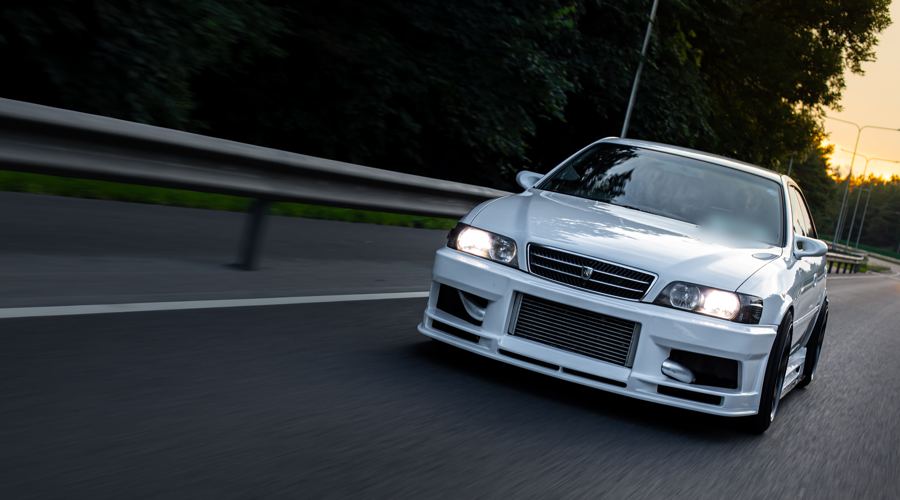 Toyota Chaser leaning into a bend with its headlights on