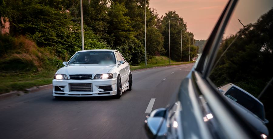 Toyota Chaser following behind, seen past a car door mirror