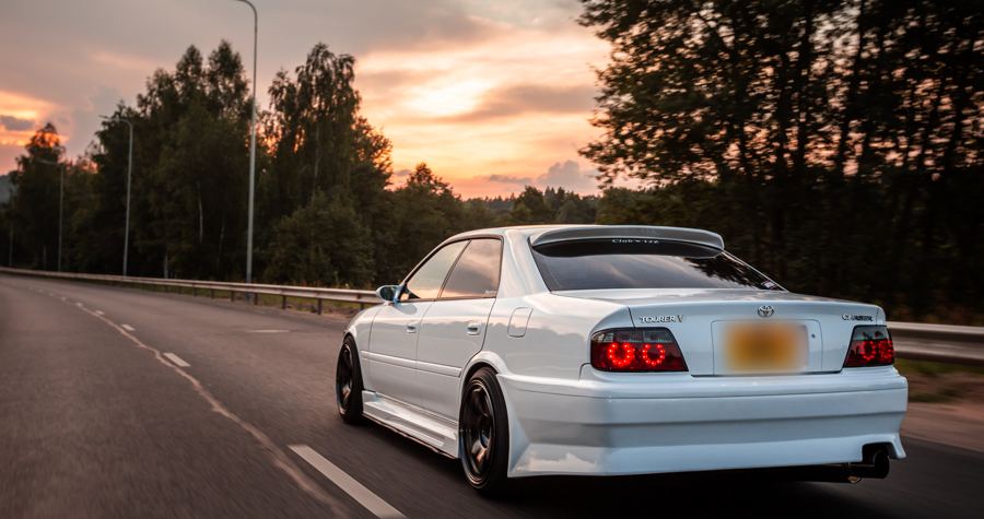 Toyota Chaser on a tree-lined road under a pink sky