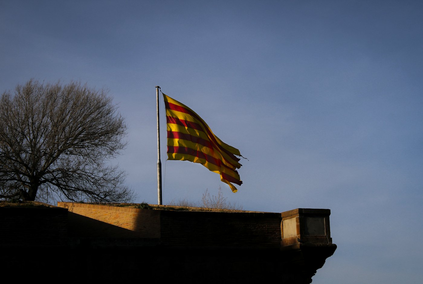 The Catalan flag flying over the walls of Montju&iuml;c Castle at dusk