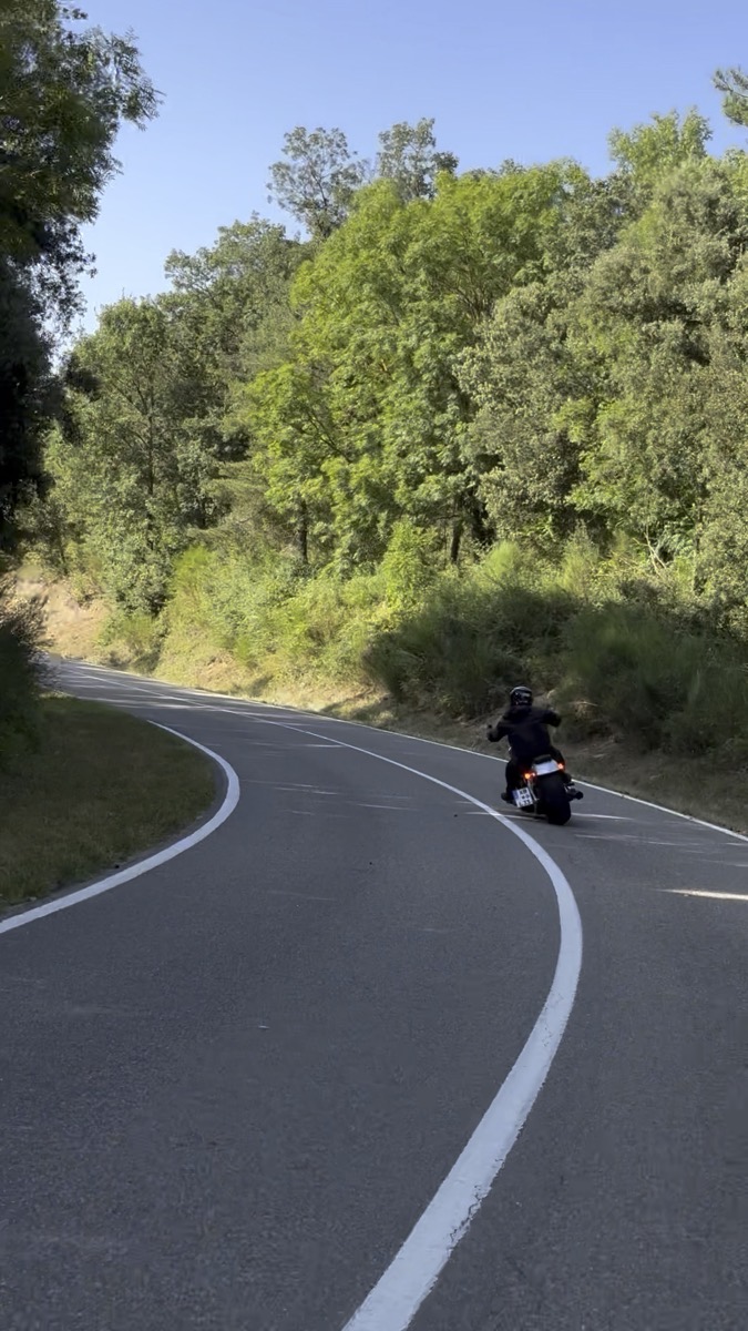 A motorcycle leaning into a curve on a Montseny road, forest on both sides