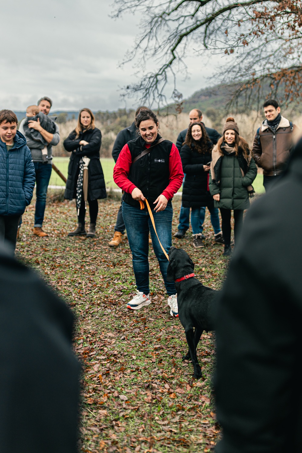 The truffle hunter with her black dog on a lead in a winter oak wood