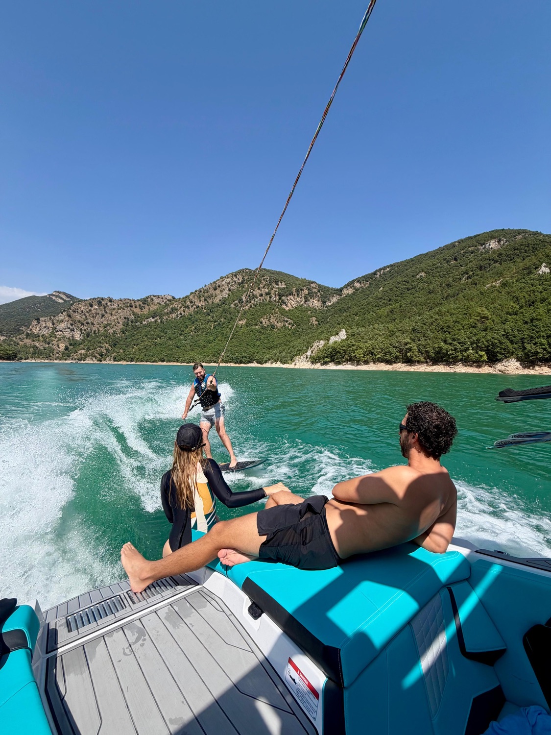 Friends on the back of the wake boat watching a rider