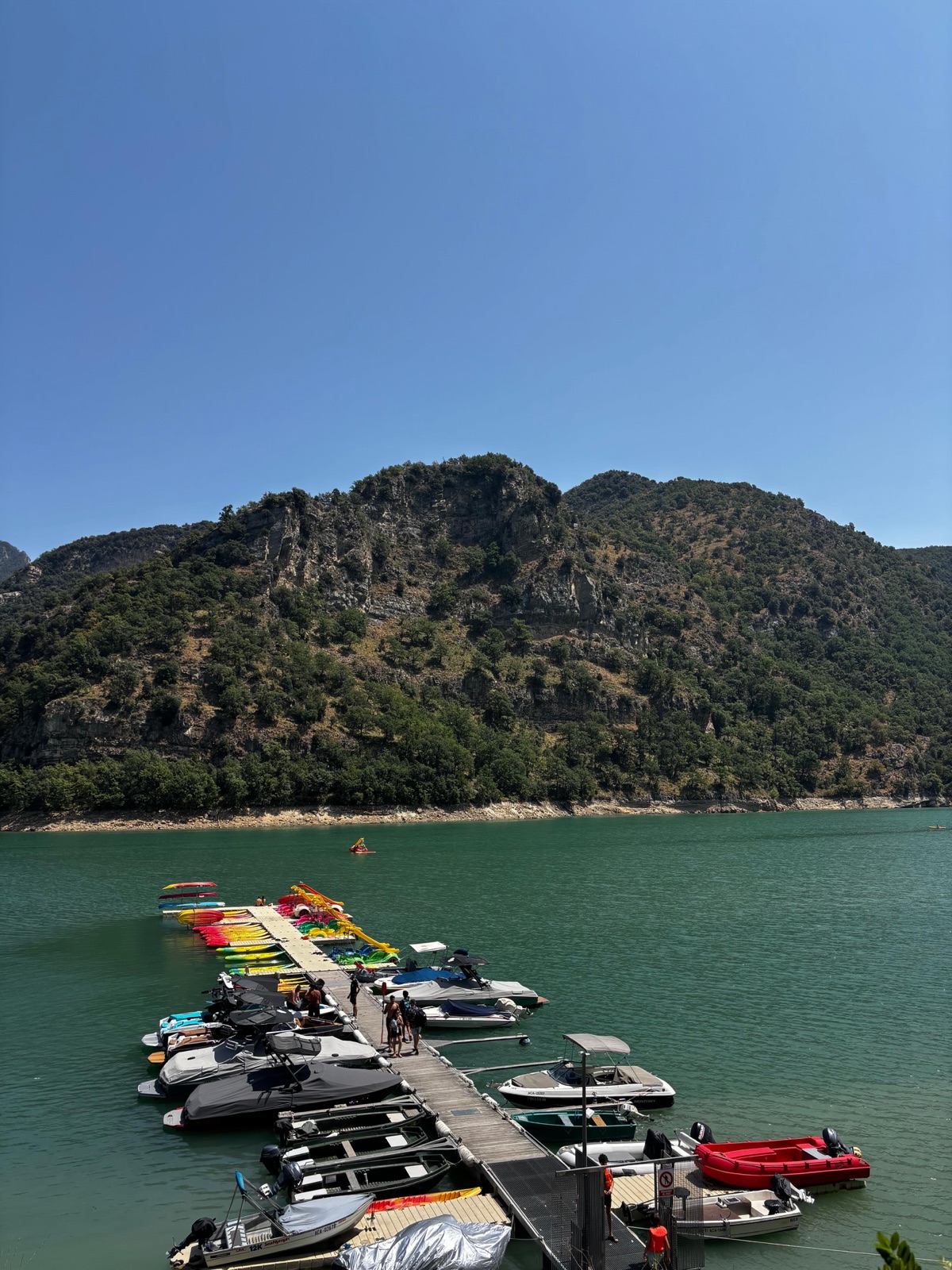 The pier on the Baells lake with boats and kayaks