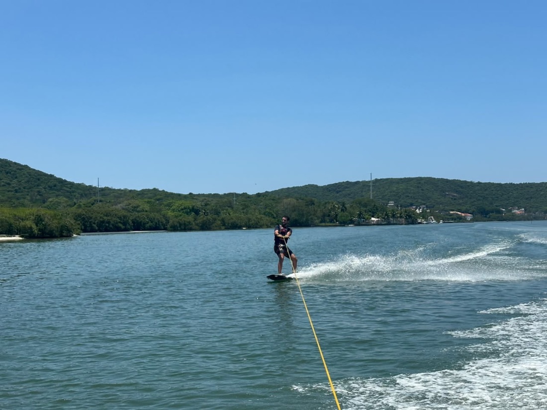Wakeboarding behind the boat, green hills behind