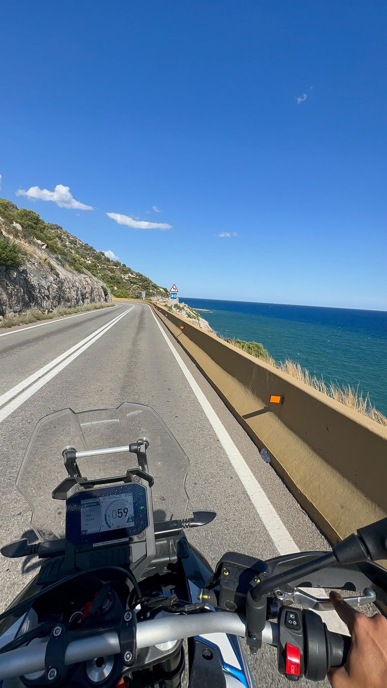 The C-31 from the saddle: the road runs along the cliff, the Mediterranean just beyond the barrier