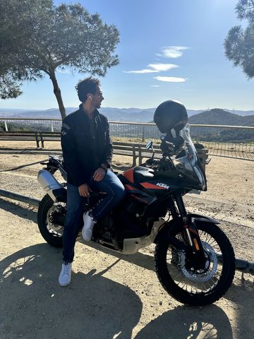 Rider sitting on an adventure motorcycle at a viewpoint in the Collserola hills above Barcelona
