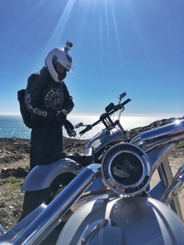 Rider beside a cruiser on the cliffs above the Mediterranean on the Costa Brava
