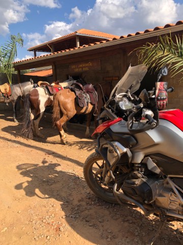 Chevaux sellés à côté d'une moto devant un bâtiment de ferme au Minas Gerais