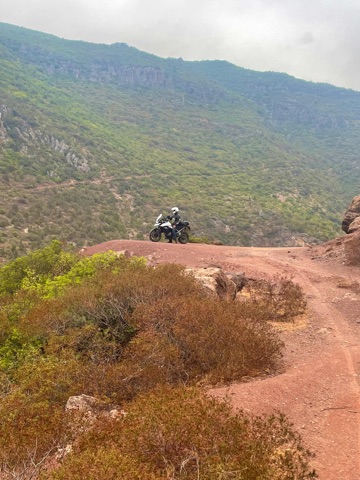 Adventure motorcycle on a red earth track along a ridge in the Moroccan hills