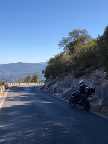 Motorcycle parked on a mountain road in the Andalusian sierra with the range behind