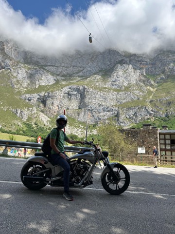Rider on a chopper below the Fuente D&eacute; cable car, with the limestone wall of the Picos de Europa behind