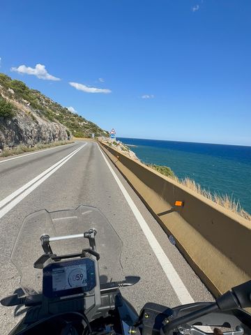 View over the handlebars of a motorcycle on the C-31 Garraf coast road, with the sea on the right