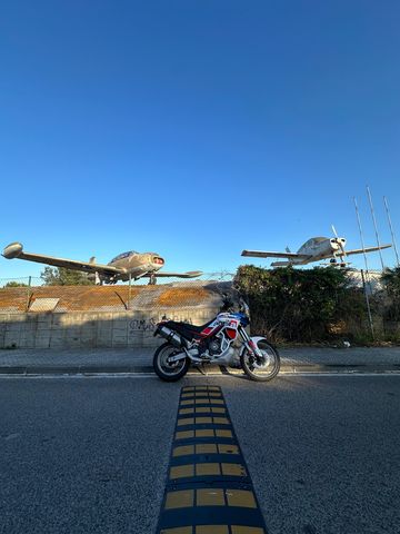 Adventure motorcycle on the road in Vilanova i la Geltr&uacute;, with two aeroplanes on display behind it