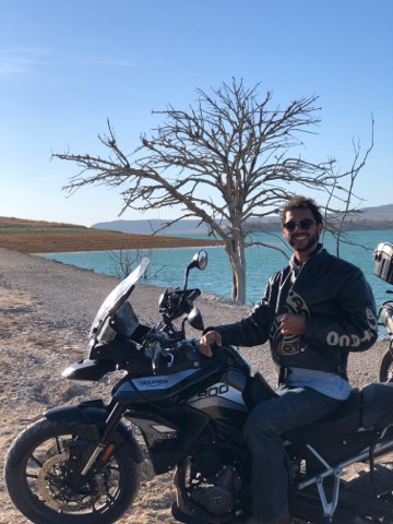 Rider beside a reservoir with a bare tree in southern Spain