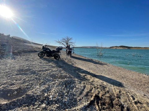 Motorcycles on a stony shore beside clear water near Tarifa