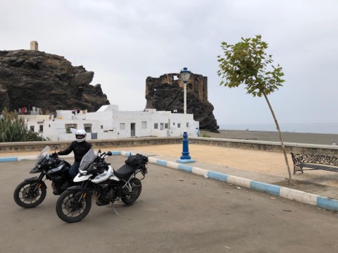 Motorcycles below a hilltop fortress in a white village near Tarifa