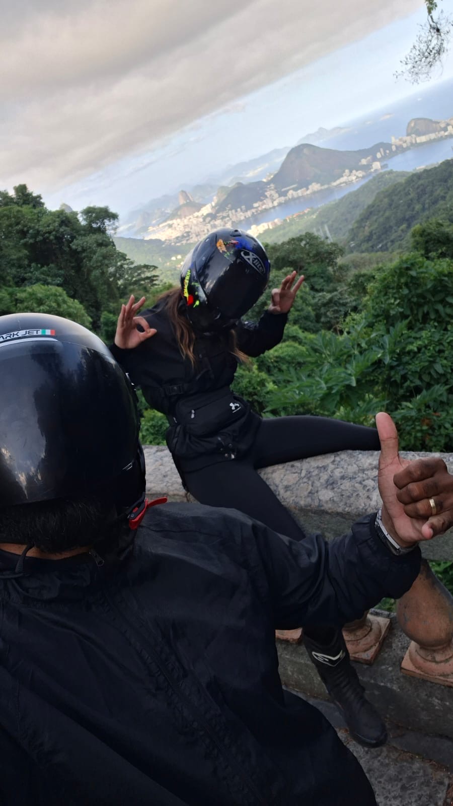 Beifahrerin mit Daumen hoch vom Soziussitz auf einer Waldstraße in Rio