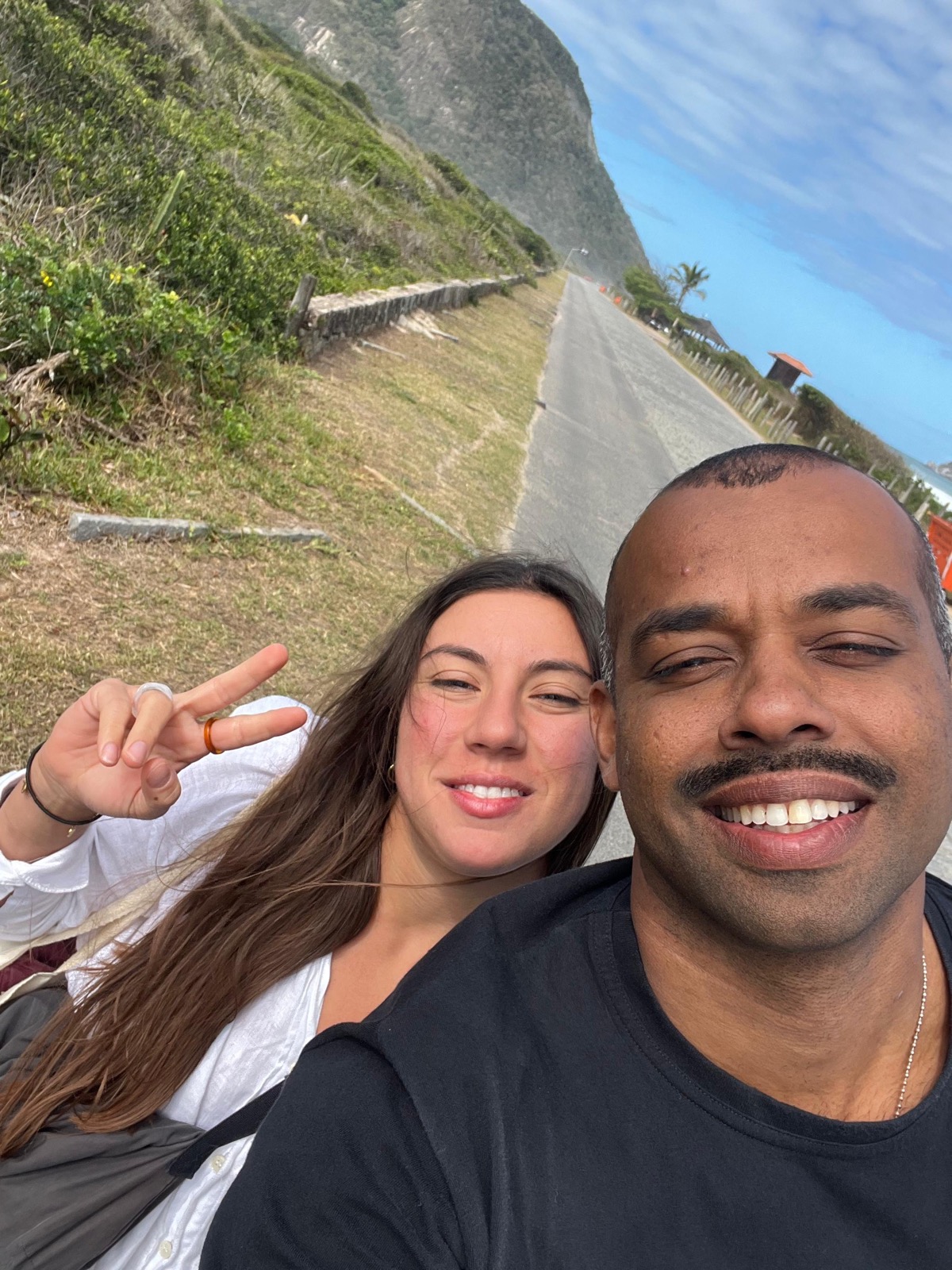 Beifahrerin und Pilot lächeln für ein Selfie auf einer Küstenstraße in Rio